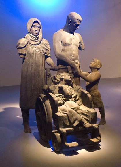 Operation Iraqi Freedom Family (2016) by MAHMOUD OBAIDI. To create this life-size sculpture, the artist mixed discarded American weapons and Humvee parts with melted bronze. The entire process took several months. Referring to the sculpture, Obaidi remarked, “It says this is what you did to us.”