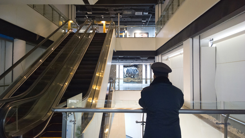 A security guard gazes at his distorted reflection in MAO TONGQIANG’s Order (2015), which was perforated by bullets fired from a Type 92 pistol.