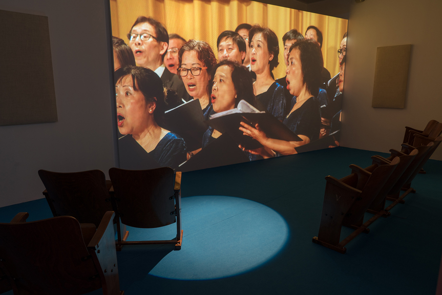 Installation view of SAMSON YOUNG’s We Are the World, as performed by the Hong Kong Federation of Trade Unions Choir, 2017, eight-channel video installation with sound, dimensions variable, at “Samson Young: Songs for Disaster Relief World Tour,” M+ Pavilion, Hong Kong, 2018. Courtesy the artist, West Kowloon Cultural District Authority and M+ Museum, Hong Kong.