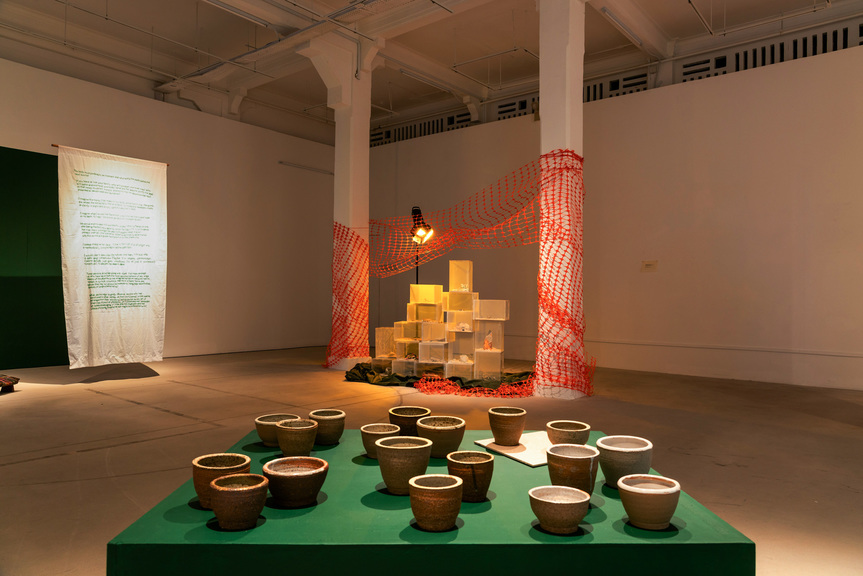 Installation view of (front) SURIANI SURATMAN’s Ramuan, 2021, ceramics, dimensions variable; and (back) FAZLEEN KARLAN’s Hanya Tinggal Kenangan, 2020– , plaster, found objects, acrylic paint, wood, sand, dimensions variable, at “ Between the Living and the Archive, ” Gillman Barracks, Singapore, 2021.