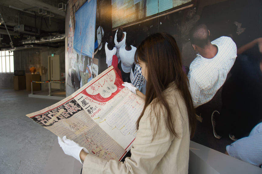 Photo of assistant reading ROBEL TEMESGEN’s Addis newspaper—The Chinese Issue—January 2050, 2014, mixed media, 50.5 × 34.5 cm each, at “Curtain,” Para Site, Hong Kong, 2021. Photo by Samson Cheung Choi Sang. Courtesy the artist and Para Site.